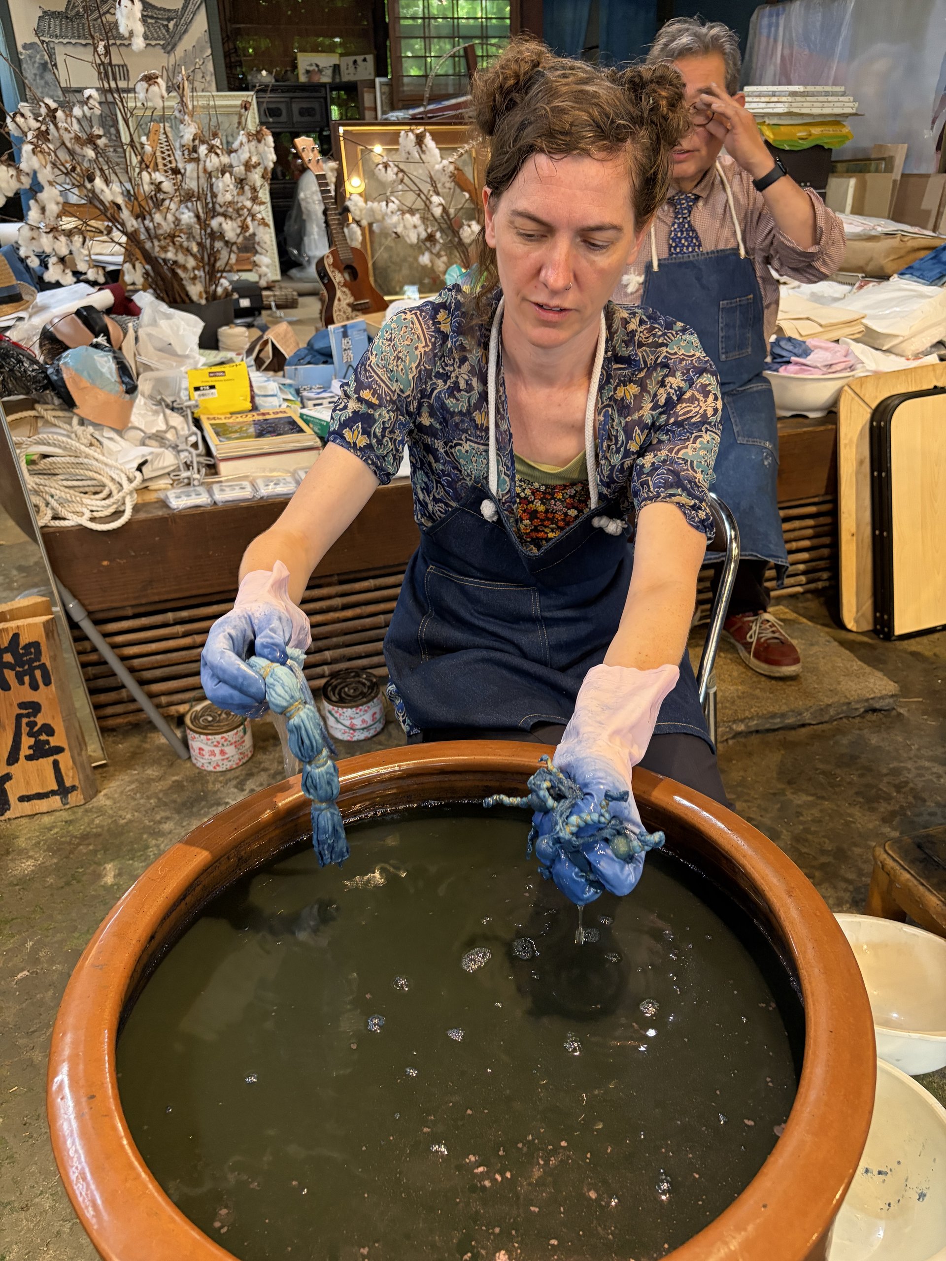 Guest lifting freshly indigo-dyed cloth from the dye vat